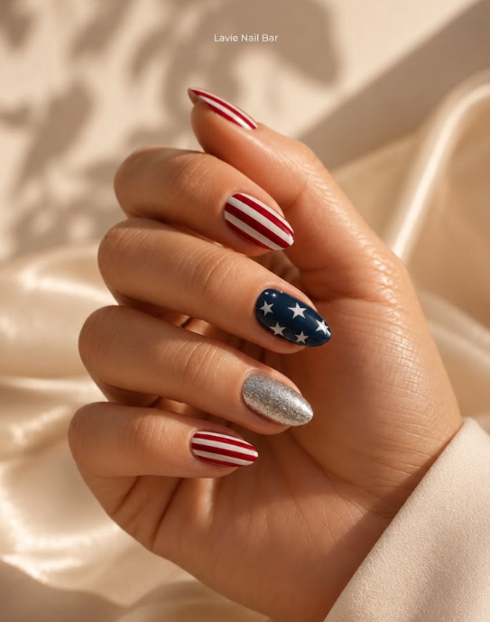 Elegant almond nails with red stripes, a navy star accent, and a shimmering silver nail